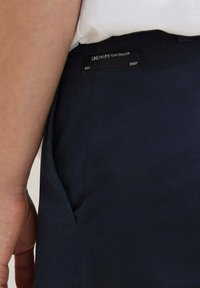 Granatowe spodnie o gładkiej teksturze, z boczną kieszenią i czarną metką z białym napisem "DENIM TOM TAILOR EST. 2007."