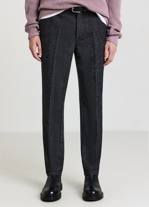 Pantaloni neri con trama testurizzata e motivo sottile, vestibilità slim, pieghe frontali e finitura liscia. Indossati con un maglione rosa e scarpe nere.