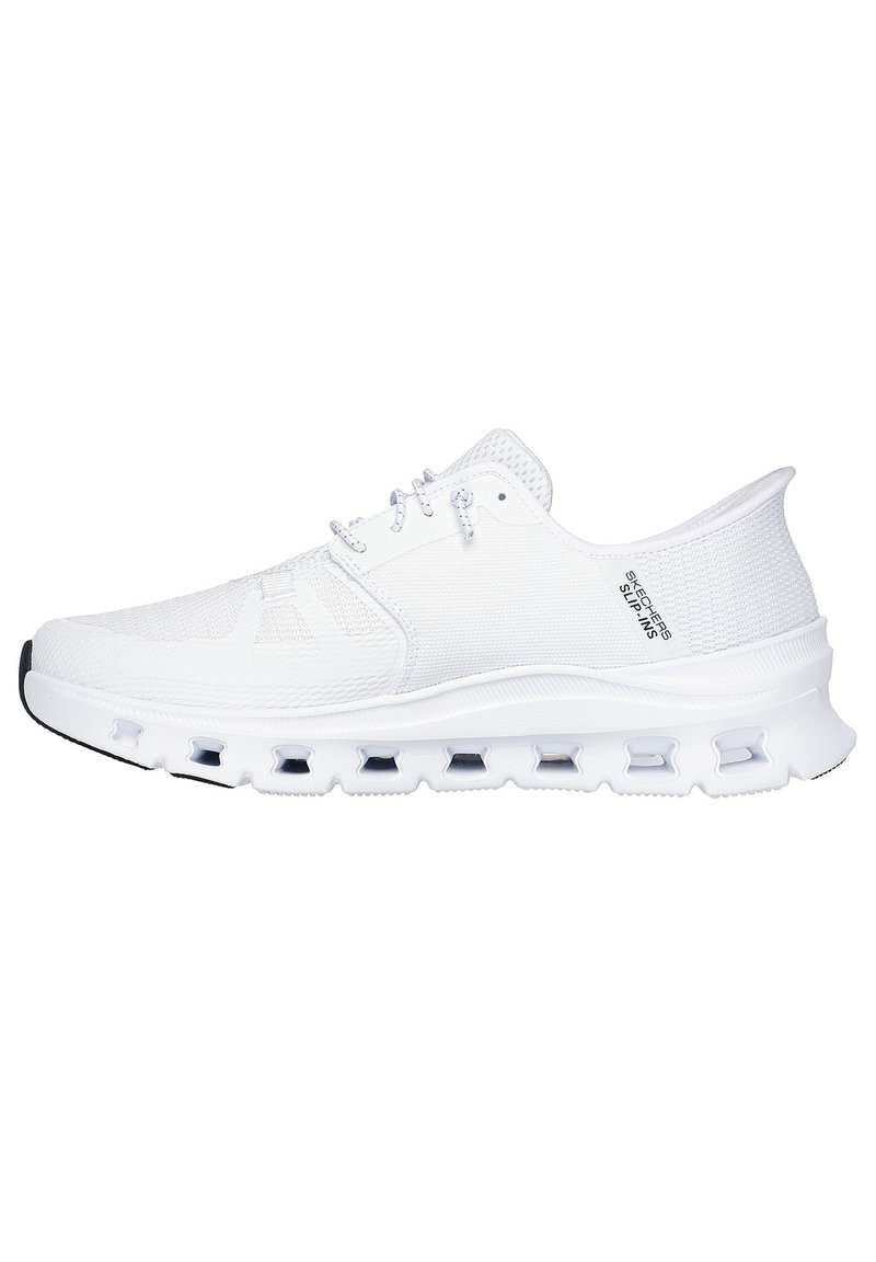 Zapatilla deportiva blanca con parte superior de malla, diseño de cordones, cuello acolchado y una suela gruesa y texturizada que presenta elementos de amortiguación visibles.