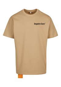 Tan bomulds t-shirt med korte ærmer, rund halsudskæring og sort tekst "forgotten faces" foran. Har et orange mærke i kanten.