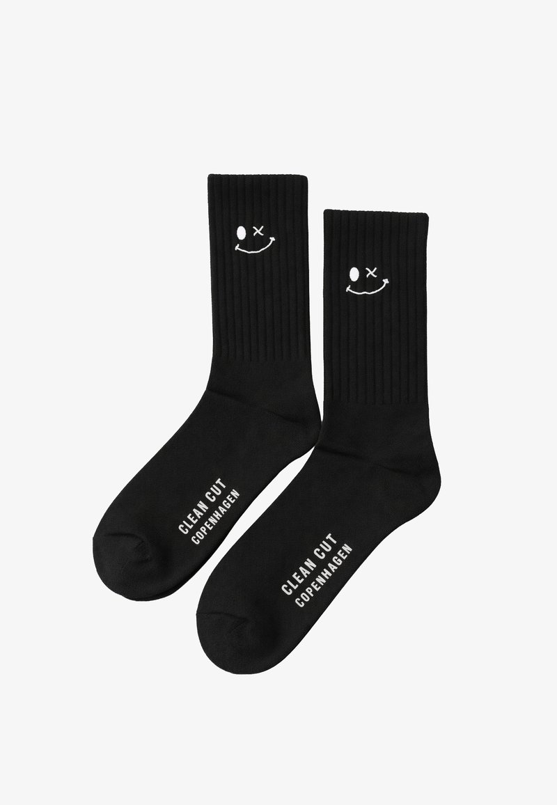 Schwarze, gerippte Kurzsocken mit weißen, lächelnden Gesichtern nahe der Oberseite und dem Schriftzug "Clean Cut Copenhagen" im Fußbereich.