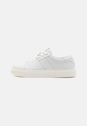 Sneaker in pelle bianca con texture liscia, punta tonda, design con lacci, branding minimalista e suola in gomma bianca a contrasto.