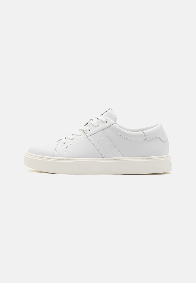 Sneaker in pelle bianca con texture liscia, punta tonda, design con lacci, branding minimalista e suola in gomma bianca a contrasto.