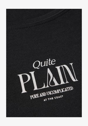 T-shirt in cotone nero con testo stampato in bianco. Il design include "Quite PLAIN" e "PURE AND UNCOMPLICATED AT THE COAST" in diversi caratteri.