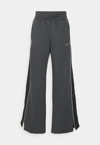 Mörkgrå vida sweatpants med dragsko i midjan, vita sidostreck och en liten Nike-logotyp på vänster framsida. Mjuk tygkänsla.