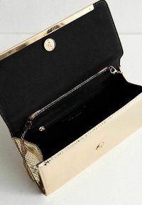 Borsa a busta sintetica oro con finitura testurizzata, interno nero, chiusura a scatto in metallo e tracolla a catena. Presenta una tasca con zip all'interno.