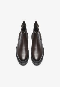 Bottines Chelsea en cuir marron avec une finition lisse, bout arrondi, panneaux latéraux en élastique et semelle en caoutchouc basse.