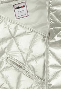 Srebrna kurtka ocieplana, pikowana, zapinana na zamek, z metką rozmiaru 8-9 lat. Wewnętrzna podszewka jest gładka. Wierzch wydaje się błyszczący i metaliczny.