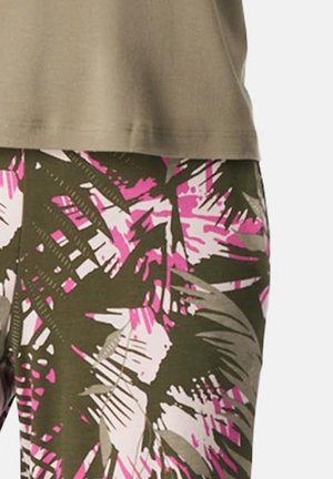 Oliwkowo-zielony top o luźnym kroju zestawiony z dopasowanymi spodniami ozdobionymi różowo-szarym tropikalnym wzorem liści. Miękka tkanina, widoczne przeszycia.