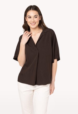 Brown short-sleeve shirt with a V-neck, lightweight texture, and folded sleeves, paired with white pants.