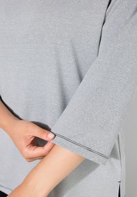 Camicia a righe grigie con una vestibilità comoda, collo a giro, e maniche corte con dettagli di cucitura a contrasto. Tessuto liscio e leggero.
