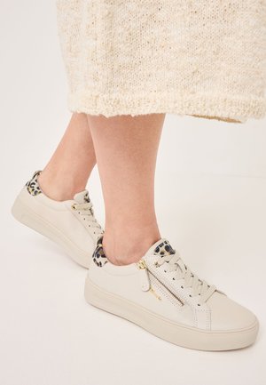 Light beige sneakers with leopard print accents, textured leather, lace-up design, and side zippers for added detail.