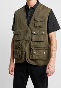 Olivgrüne Utility-Weste mit mehreren Taschen, Reißverschluss und Druckknöpfen. Verfügt über einen legeren Schnitt und eine strapazierfähige Stofftexture.