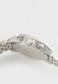 Edelstahl-Chronographenuhr mit rundem Gehäuse, strukturiertem Lünette, drei Drückern und einem Gliederarmbanddesign.