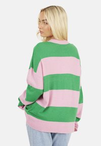 Maglione oversize con strisce orizzontali verdi e rosa. Tessuto lavorato a maglia, polsini a coste e scollo rotondo. Design casual.