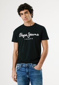 Crni pamučni majica s bijelim kurzivnim logom "Pepe Jeans London." Kratki rukavi, okrugli izrez i jednobojni dizajn.