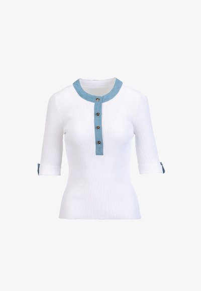 Chemise blanche côtelée avec un col bleu clair et une patte de boutonnage, dotée de manches trois-quarts et de poignets retroussés. Les boutons sont en métal.