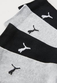 Trois paires de chaussettes en noir, gris et blanc, avec une texture côtelée et un petit logo sur chacune.
