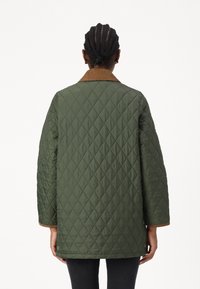 Πετσετέ πράσινο σακάκι με καφέ καρό λαιμό, φαρδιά μανίκια και κουμπιά στην άκρη, με διαμαντένιο σχέδιο σε όλη την επιφάνεια.