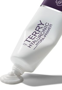 Hyaluronische primer in een witte knijpfles met een paarse dop. Benadrukte merknaam en productdetails gedrukt in donkerpaars. Romige textuur die eruit komt.