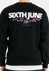 Zwarte sweatshirt met opvallende witte en roze tekst op de achterkant. De tekst bevat "SIXTH JUNE" en "La vie en Rose." Soepele stof, relaxte pasvorm.