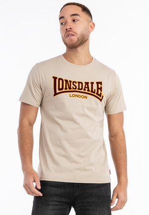 Bež bombažna majica s kratkimi rokavi, ki na prsih vsebuje velik maroon Lonsdale London logotip. Klasičen kroj z okroglim izrezom.