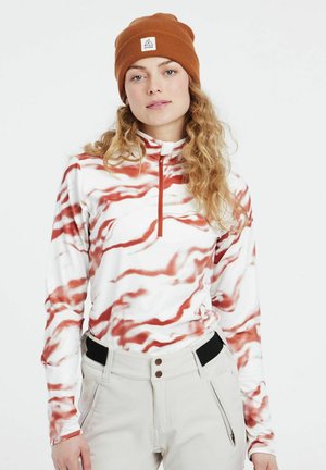 Kwart-rits top met een witte stof met rode golvende patronen, lange mouwen en een hoge kraag. Gecombineerd met lichte broek.