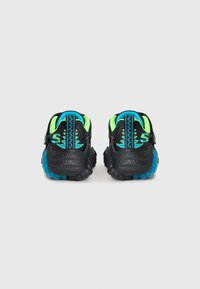Black athletic shoes with blue and neon green accents, textured rubber soles, and a unique design featuring zigzag patterns on the heel.