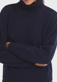 Navyblauer Rollkragenpullover aus weichem Strickmaterial, mit gerippten Bündchen und Saum, lockerem Schnitt und heruntergesetztem Schulterdesign.