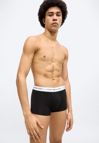 Μαύρα μποξεράκια από βαμβάκι με λευκή ελαστική μέση. Η μέση διαθέτει το λογότυπο «Tommy Hilfiger» σε κόκκινο και μπλε.