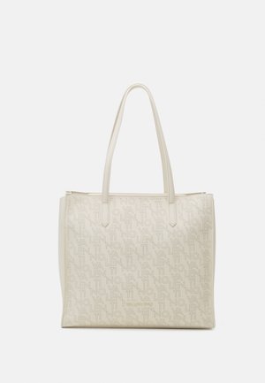 Sac fourre-tout beige avec un motif de logo en relief, doté de deux longues poignées et d'un design spacieux, fabriqué à partir d'un matériau lisse semblable au cuir.
