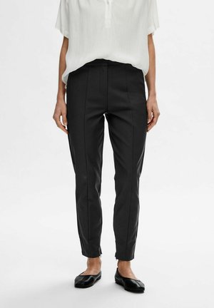Sorte skræddersyede bukser med en slim fit, der har frontfolder og lynlåse ved anklerne. Fremstillet af et glat tekstilmateriale for et rent udseende.