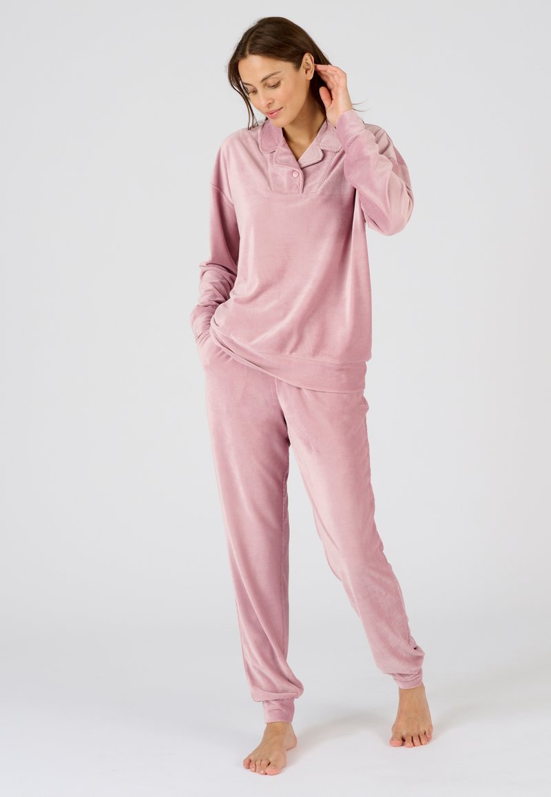 Conjunto de loungewear de terciopelo en suave rosa; presenta una blusa de manga larga con cuello y botones, y pantalones ajustados a juego con puños. Textura suave.
