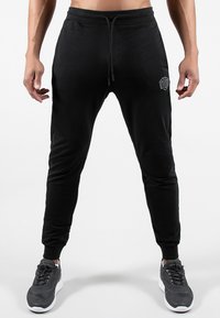 Pantaloni da jogging neri realizzati in tessuto morbido, con vita regolabile tramite cordoncino, design a gamba affusolata e un logo discreto sul lato sinistro.