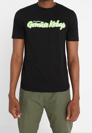 T-shirt en coton noir avec un grand texte graphique audacieux en blanc et vert "Mustafa's Gemüse Kebap" sur la poitrine. Manches courtes, col rond.