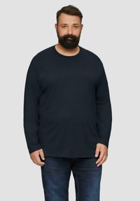 Langärmliges navy T-Shirt aus weicher Baumwolle. Mit rundem Halsausschnitt und lockerer Passform. Kombiniert mit dunklen Jeans.