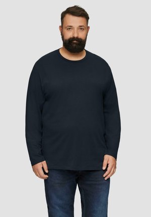 Langärmliges navy T-Shirt aus weicher Baumwolle. Mit rundem Halsausschnitt und lockerer Passform. Kombiniert mit dunklen Jeans.