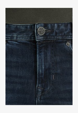 Jeans in denim blu scuro con finitura testurizzata, dotati di un bottone metallico, chiusura a zip e dettagli delle tasche cuciti. Vita ampia in colore uniforme.