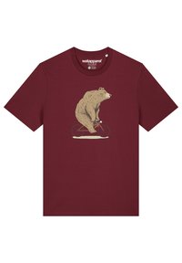 T-shirt bordeaux avec une illustration d'un ours beige montant un vélo rouge, à manches courtes et à col rond. Texture de tissu douce.