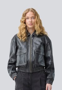 Veste bomber en cuir noir avec fermeture éclair, taille élastique et deux poches avant. Texture lisse et design cropped.