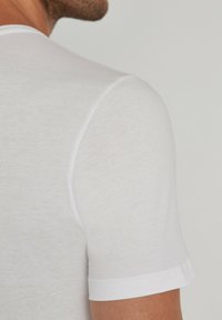 White short-sleeve t-shirt with a soft, smooth texture. Features a crew neckline and a fitted shape. Lightly heathered fabric.