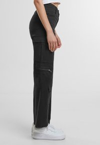 Pantaloni cargo neri realizzati in tessuto leggero, con numerose tasche, una tasca laterale con zip e una vestibilità comoda.