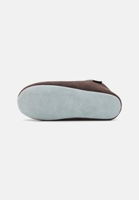 Chaussure en daim marron avec une tige texturée et une semelle en caoutchouc bleu pâle. Le design comporte un profil bas et un accent subtil près du talon.