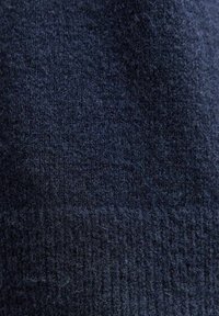 Tessuto lavorato a maglia blu navy con una texture morbida. Presenta un motivo a coste nella parte inferiore, che mette in evidenza variazioni di spessore e dimensione.