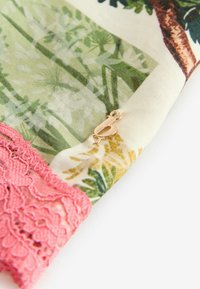 Blumengemusterter Stoff in Grün, Creme und Gelb mit einer rosa Spitzenbordüre. Verfügt über einen kleinen goldenen Verschluss. Weiche Textur.