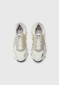 Sneaker mit einem Obermaterial aus Mesh in Weiß, Grau und Hellblau, ausgestattet mit einer dicken Sohle, Schnürverschluss und dezentem Branding auf der Zunge.