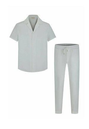 Chemise blanche à manches courtes avec boutons et col, avec un pantalon blanc à cordon, disposés côte à côte sur fond blanc.