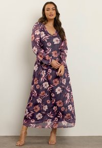 Pitkä, läpikuultava violetti mekko, jossa on vaaleanpunaisia ja valkoisia kukkakuvioita. V-pääntie ja pitkät hihat, joissa on kootut hihansuut. Lattiapituinen malli.
