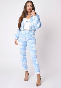 Chaqueta de mezclilla azul cielo y pantalones a juego con un patrón de nubes. La chaqueta es corta y tiene cierre de cremallera, y los pantalones cuentan con una cintura elástica.