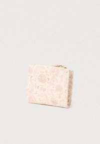 Συμπαγές μπεζ πορτοφόλι με ροζ λουλουδάτο σχέδιο και χρυσό φερμουάρ, όρθιο σε απλή ανοιχτόχρωμη επιφάνεια.